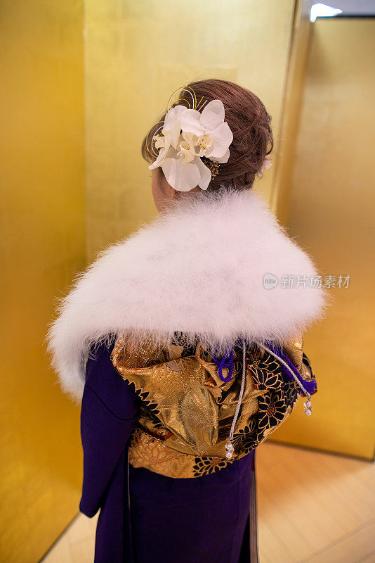 后视图的年轻女子“Furisode”和服与毛皮脖子披肩站在金色的“Byobu”折叠屏风前的“Seijin Shiki”成年仪式